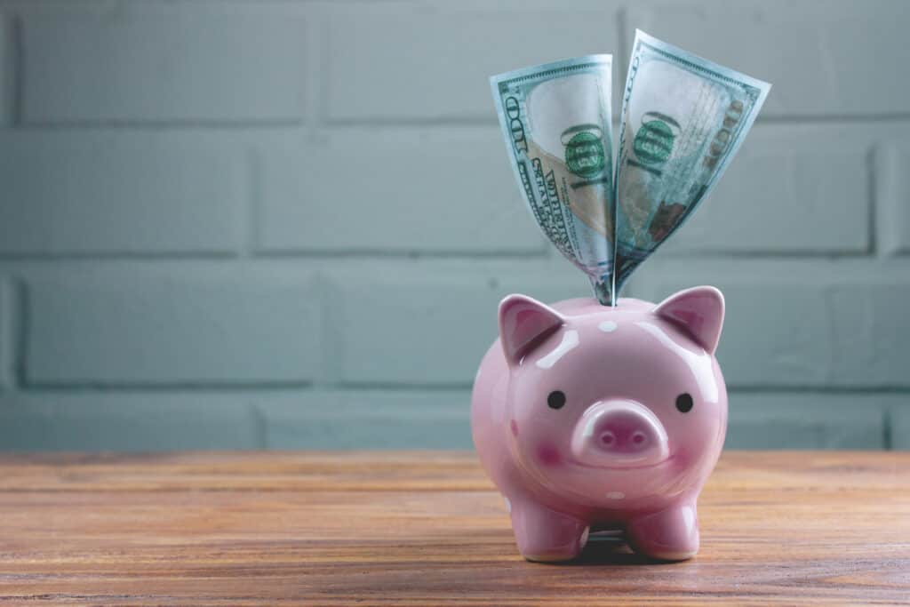 piggy bank with $100 bills coming out